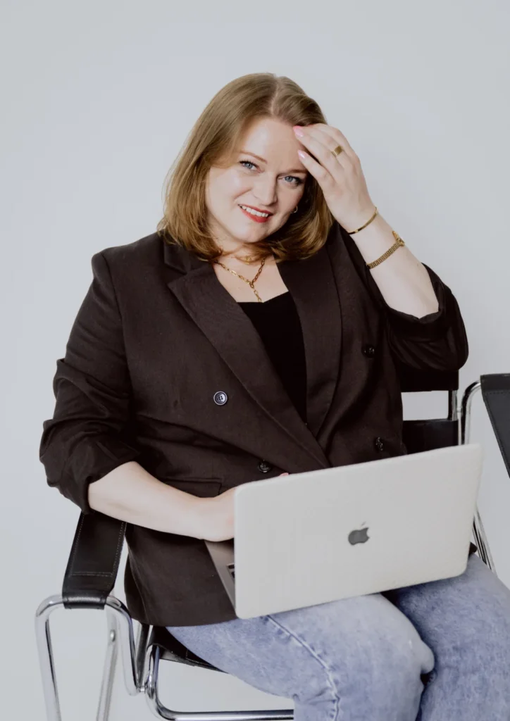 Porträt einer lächelnden Frau mit Laptop auf einem Stuhl